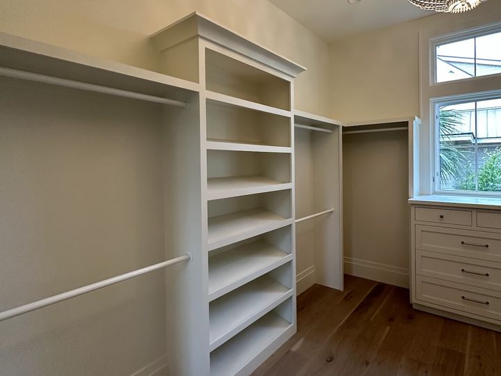 Walk in closet with shelving tower and hanging rods, by SV Construction
