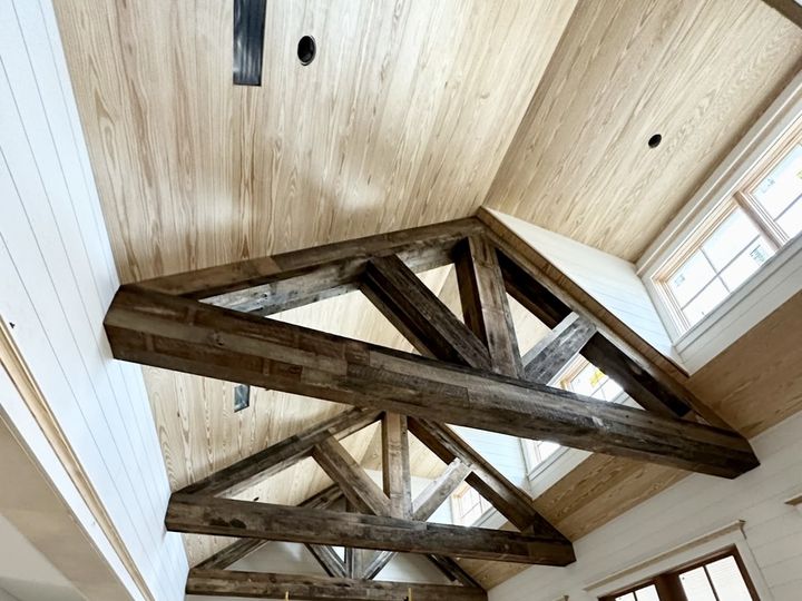 Reclaimed timber trusses under a wood plank ceiling, by SV Construction