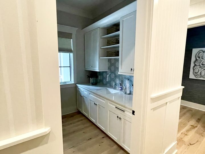 Pantry with white cabinets and patterned tile backsplash, by SV Construction